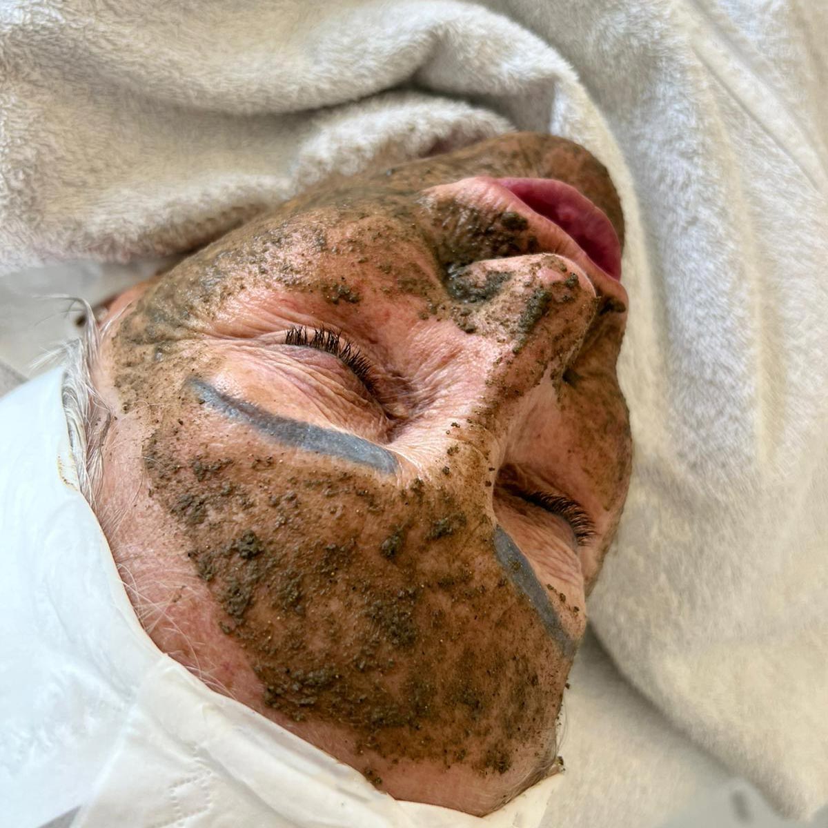 Person receiving an algae facial treatment with a green, textured mask applied to their face.